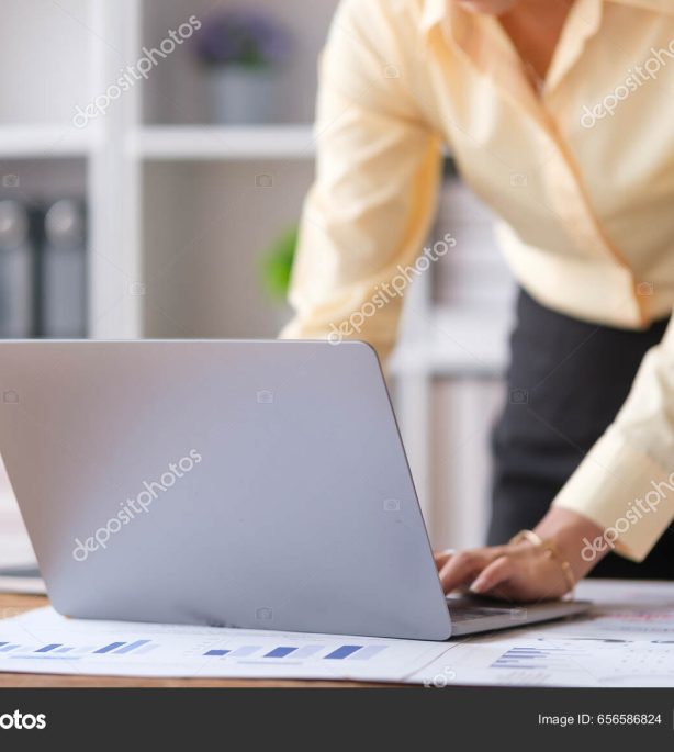 Cropped image of female office worker working on laptop computer at her dek.